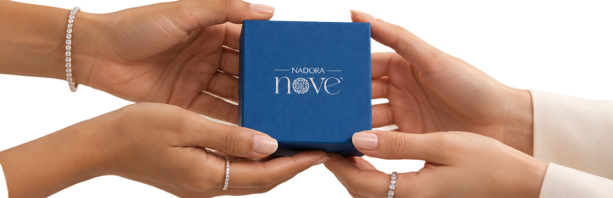 Hands holding a blue Nadora Nove jewelry box, wearing diamond bracelet and rings