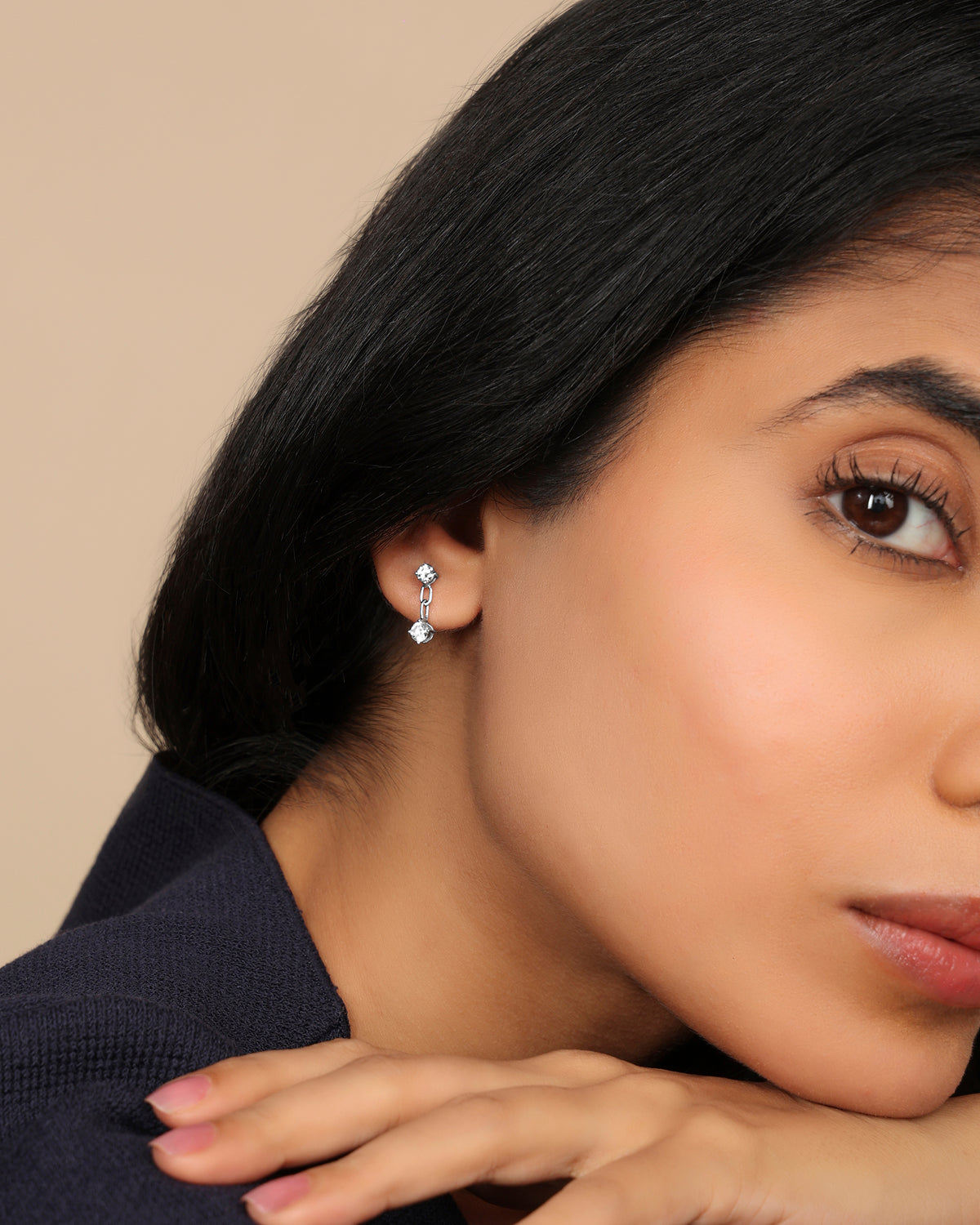 Woman wearing a Nadora Nove double diamond drop earring, resting her head on her hand in profile