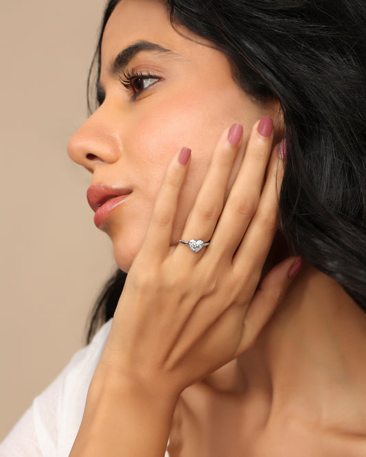 Woman wearing a Nadora Nove heart-shaped diamond solitaire ring, hand resting on her cheek in profile