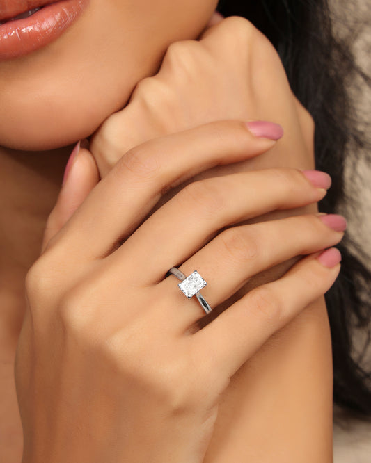 Woman wearing a Nadora Nove rectangular diamond solitaire ring, hands resting under her chin