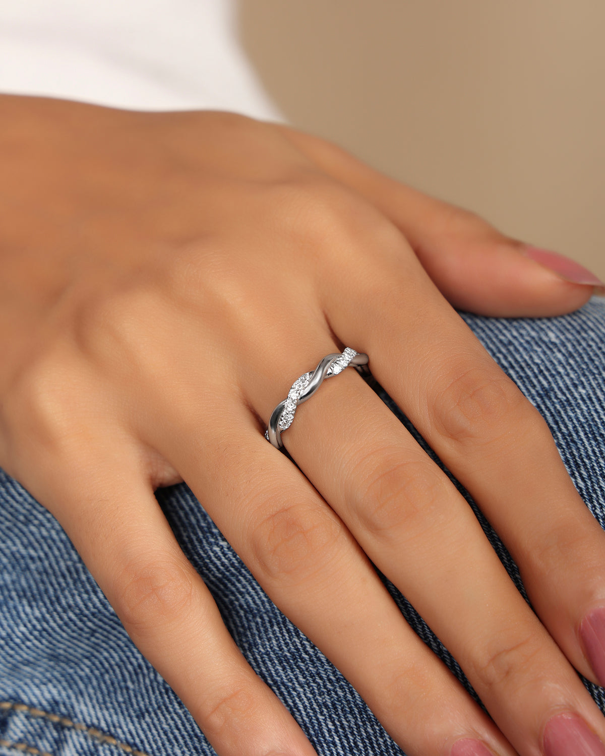 Nadora Nove twisted diamond band ring on a hand resting on denim