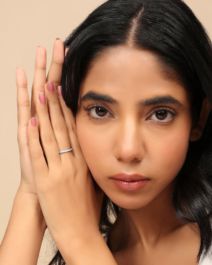 Woman wearing a Nadora Nove thin diamond eternity band ring, hands pressed together beside her face