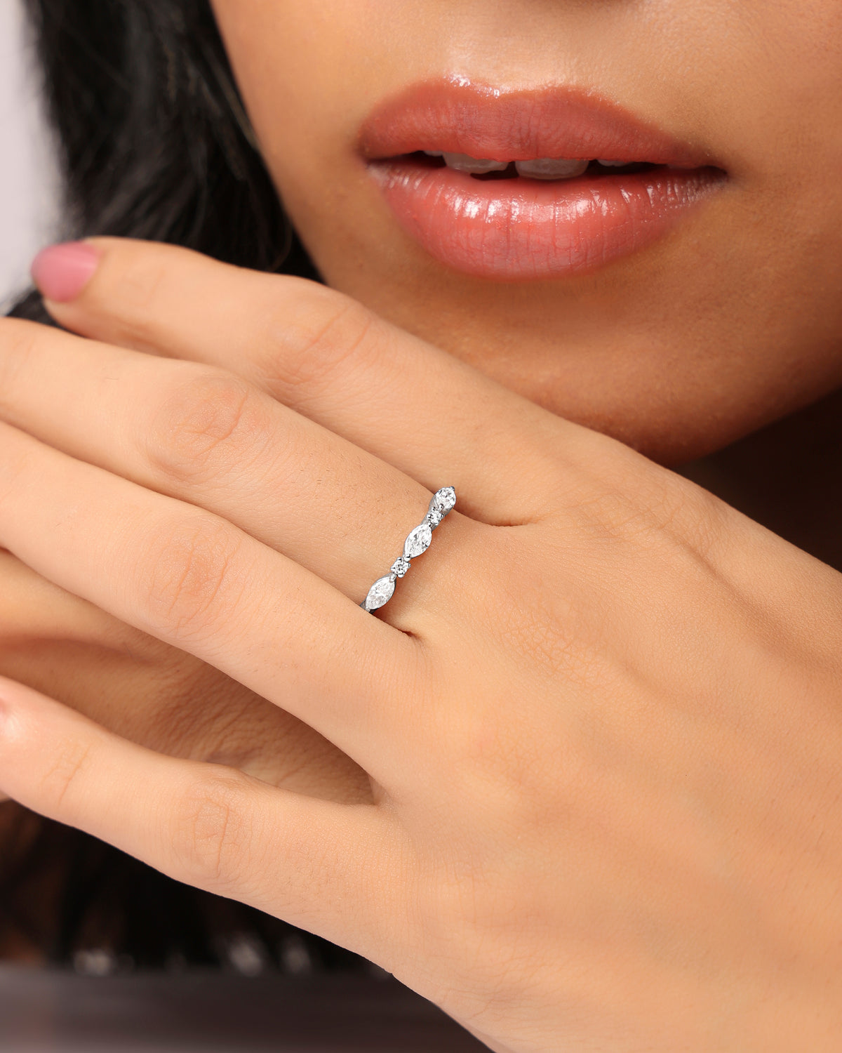 Woman wearing a Nadora Nove marquise diamond band ring, hand resting near her lips